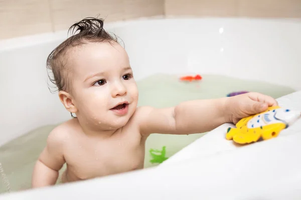 Bonito criança tomando banho com brinquedos — Fotografia de Stock