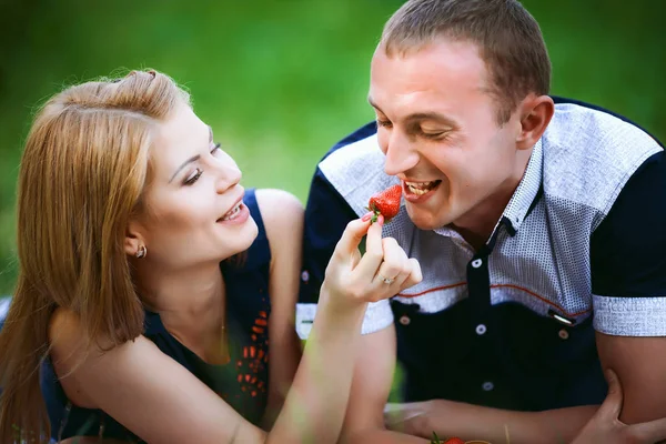 Girl feeding man a strawberry — Stock Photo, Image