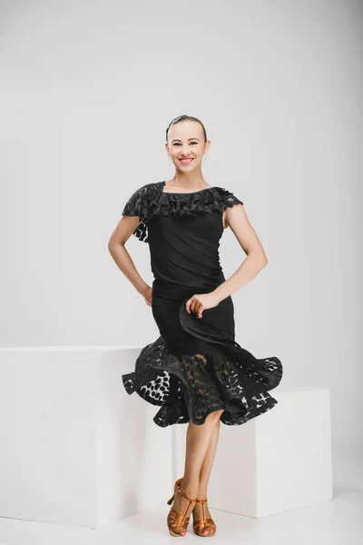Söt tjej i en svart klänning som dansar i en vit studio — Stockfoto