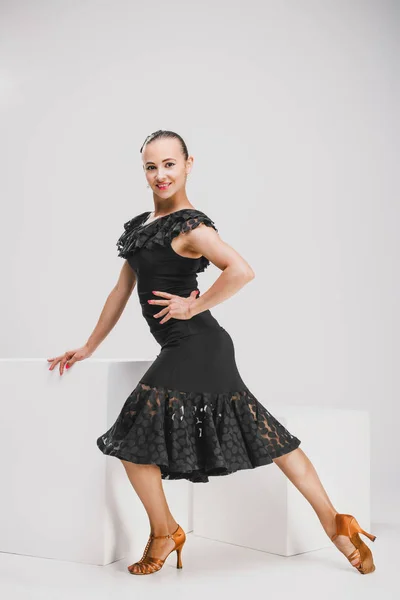 Mädchen in schwarzem Kleid tanzt im weißen Studio — Stockfoto