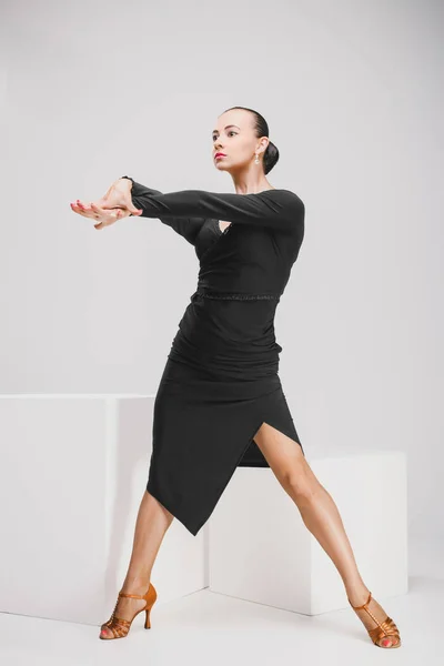 Frau in schwarzem Kleid tanzt in weißem Studio — Stockfoto