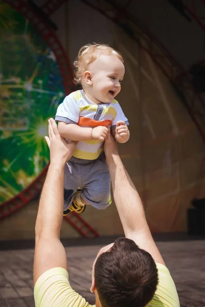 Padre divertido sosteniendo a su hijo sobre su cabeza — Foto de Stock