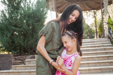 Güzel anne ve kızı oynamaya ve park merdivenlerde gıdıklıyor