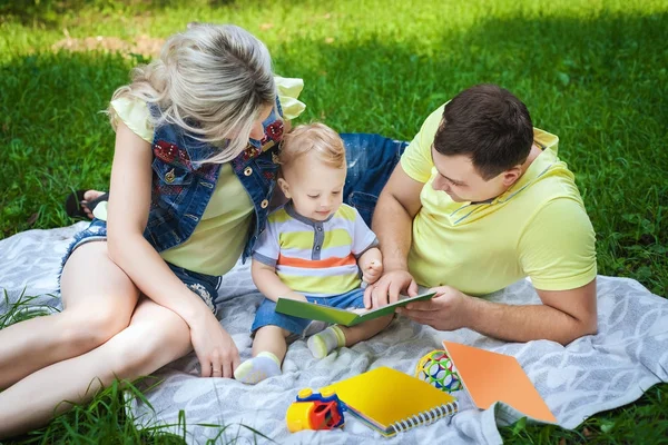 Lycklig familj läsa bok i parken Stockbild