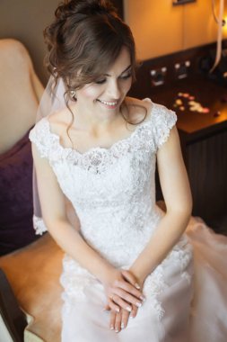 Gülümseyen ve damat için sabah bekleyen sandalyede oturan güzel gelin