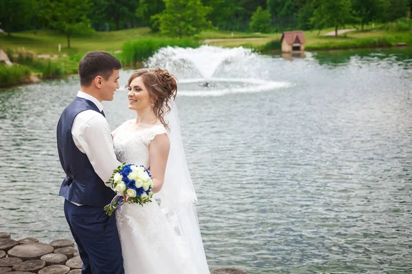 Güzel gelin ve damat doğa göl yakınındaki çeşme ile gülümseyen — Stok fotoğraf