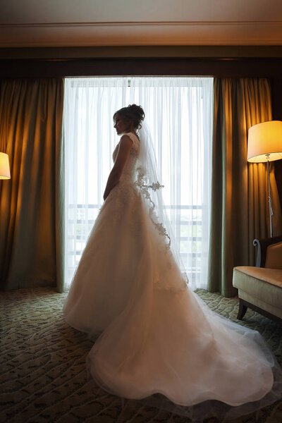 Attractive stylish brunette bride near a window in luxury room