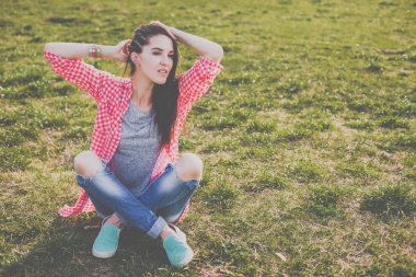 yeşil çayır üzerinde oturan sevimli hipster teen