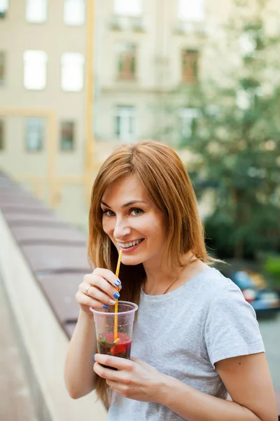 redhead female drinking cocktail in the street