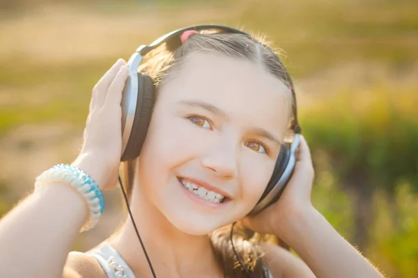 Dítě poslouchá hudbu se sluchátky a usmívá se — Stock fotografie