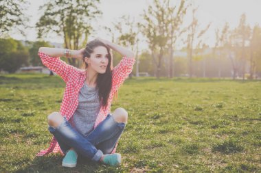 yeşil çayır üzerinde oturan sevimli hippi kız