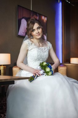 Sandalyede oturan düğün çiçekleri ile genç gelin