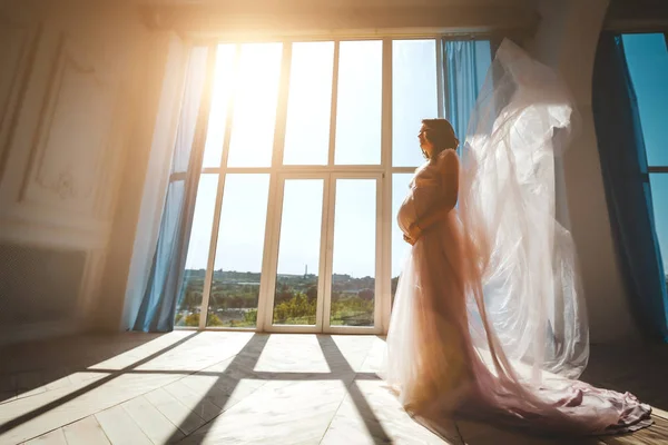 Молода красива вагітна модель, що стоїть біля вікна — стокове фото