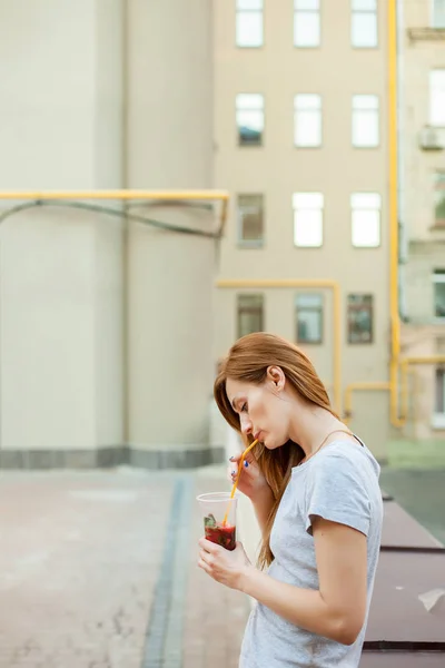 redhead model drinking cocktail in the street