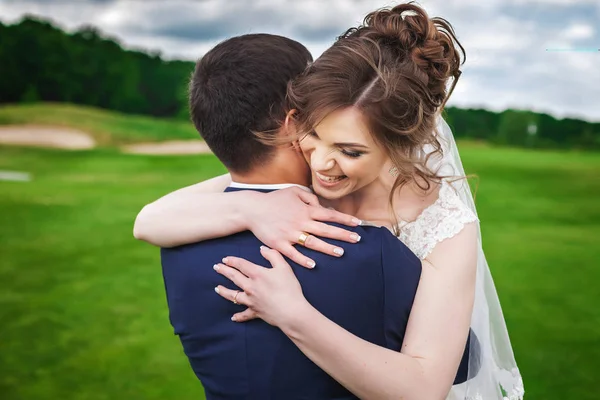 Bride hugging her groom and smiling in nature — Stock Photo, Image