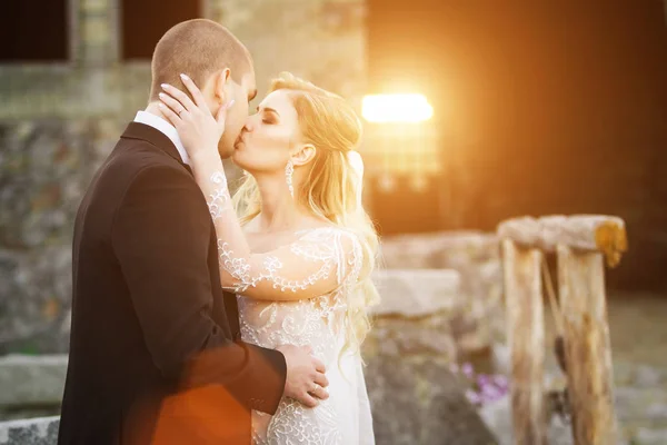 Gelin ve damat öpüşme yakınındaki hafifleyen günbatımı kurarak