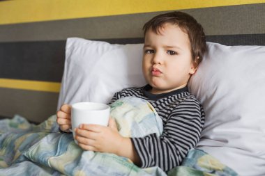 üzgün hasta kür bebek çocuk ilaç alarak yatağın üstüne oturuyor