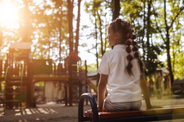 Kız bankta oturuyor.
