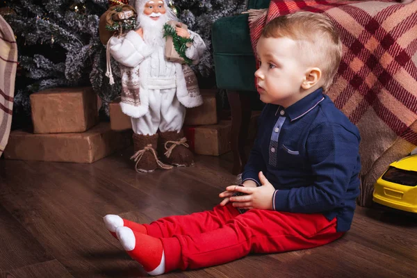 크리스마스 장식 옆에서 장난감 자동차를 하고 있는 소년 — 스톡 사진