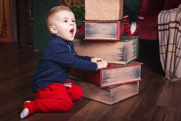 크리스마스 때 책 옆에 앉아 있는 어린 소년 — 스톡 사진