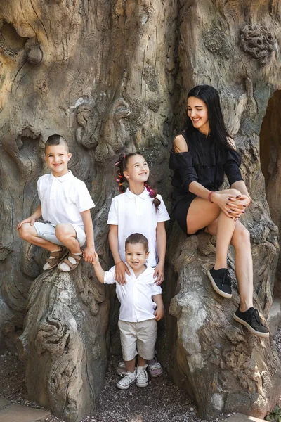 Mother with her kids sitting on the tree stem — Stock Photo, Image