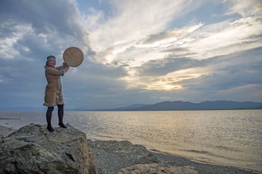 Evenki woman at sunset with a tambourine encourages spirits clipart