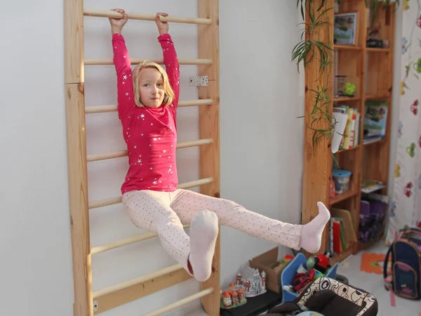 Mädchen treibt Sport an Sprossenwand im Kinderzimmer lizenzfreie Stockbilder