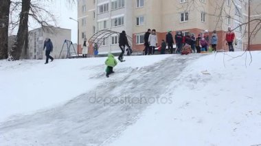 Brest, Belarus - 17 Ocak 2016. Çocuk buzlu tepeden kızaklarımız üzerinde kaydırın. Kar slaytlar geleneksel çocuk oyun açık havada kışın kayak.