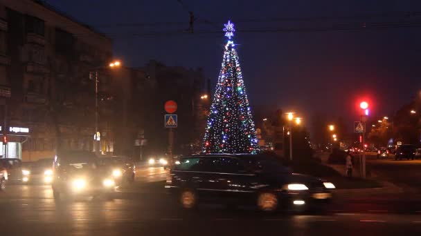 Brest, Bělorusko - 13 prosinec 2015. Svítící vánoční strom na ulici v noci. Boulevard kosmonauti, busy provozu. — Stock video