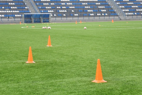 Kužele a koule pro fotbalový trénink na stadionu. Sportovní zázemí. — Stock fotografie