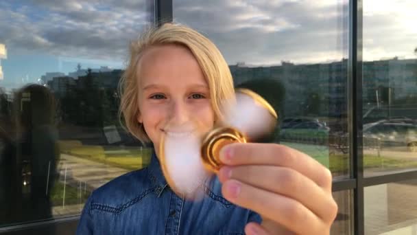 Schöne fröhliche Schulmädchen, die mit einem goldenen Fidget Spinner spielt. ein beliebtes trendiges Spielzeug. — Stockvideo