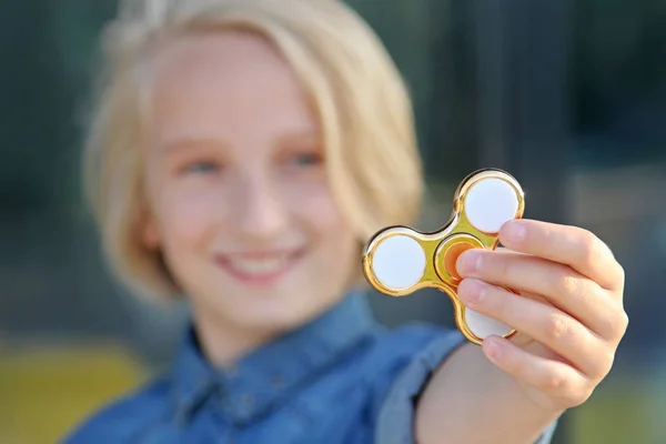 Cheerful school aged girl playing with a gold fidget spinner. A popular trendy toy. — Stock Photo, Image