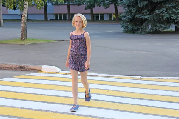 Una niña en edad escolar cruza la calle en un cruce peatonal —  Fotos de Stock