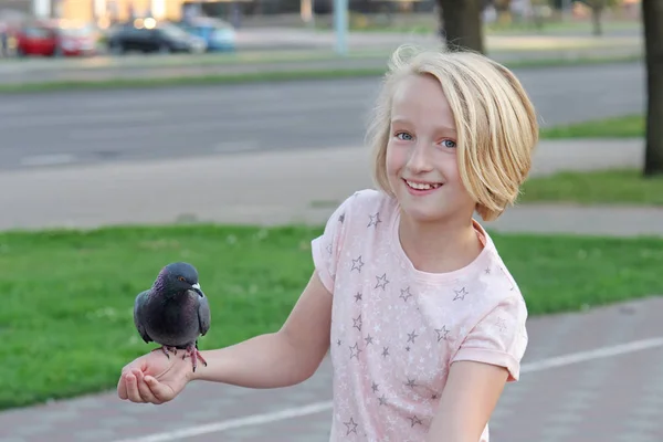Jovem alimenta um pombo com as mãos na rua da cidade — Fotografia de Stock