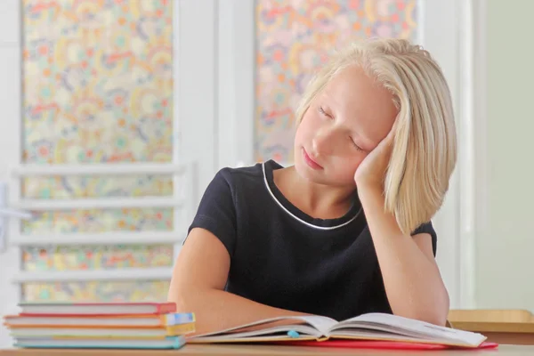 Müdes Schulkind schläft während einer Unterrichtsstunde am Schreibtisch in einem Klassenzimmer lizenzfreie Stockbilder