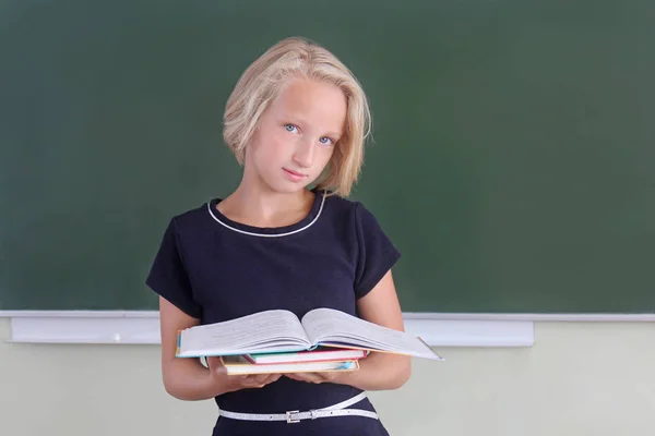 Очаровательная блондинка с книгами в классе возле доски. Возвращение в школу . — стоковое фото