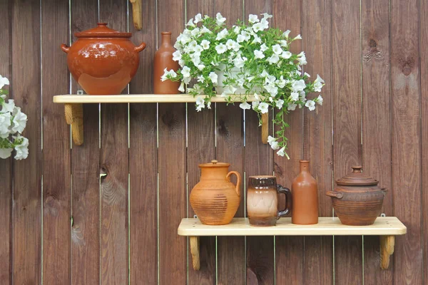 Keramik kannor och krukor stå på en hylla mot bakgrund av en trävägg — Stockfoto