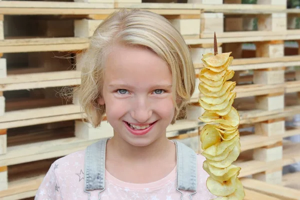 女孩吃薯片在棍子。垃圾食品, 街头小吃, 散步零食. — 图库照片