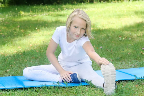 穿着浅色衣服的适龄女孩在公园的垫子上做运动运动 户外锻炼 — 图库照片