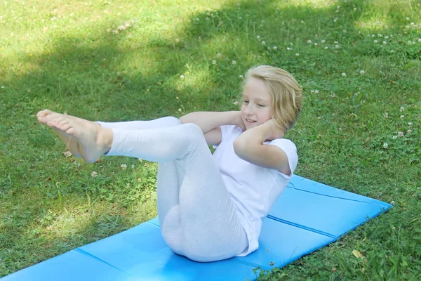 Güzel sarışın varoluş kız ışık giyim pratik yoga mat parkta. Sağlıklı bir yaşam tarzı. Açık havada egzersiz. 
