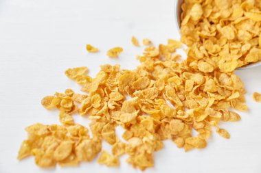 Plaser ile boyalı Beyaz ahşap zemin üzerinde metal bir kase mısır gevreği. Ahşap bir masa üzerinde dağınık Mısır gevreği.