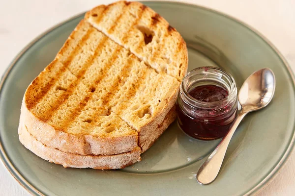 Toast with cherry jam on a white wooden table. Fried bread on a gray shiny plate. — Stock Photo, Image