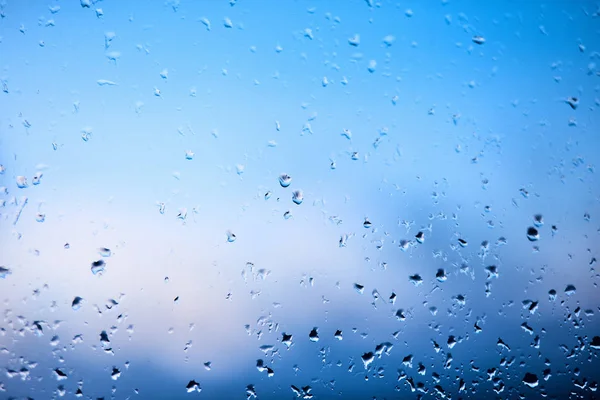 Gotas de lluvia en el parabrisas del coche por la mañana temprano. Vidrio transparente después de la lluvia, foto abstracta fría. Textura de vidrio con gotas de lluvia dispersas y un fondo borroso al final de la noche . —  Fotos de Stock