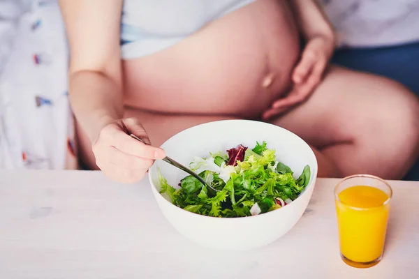 Witte kom met groene en rode salade. Oranje, pompoen, wortel, mango sap op een houten tafel. Gezonde voeding voor de zwangerschap. Dieet voor zwangere vrouwen en meisjes. Het concept van gezond eten en zwangerschap. Stockfoto