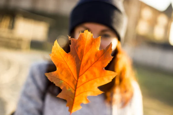 Fille aux cheveux roux dans un manteau gris et un chapeau bleu avec des feuilles d'automne jaunes. atmosphère. authentique — Photo