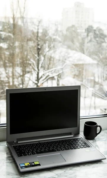 Laptop számítógép áll a márvány tábla az ablak, egy csésze kávé mellett — Stock Fotó