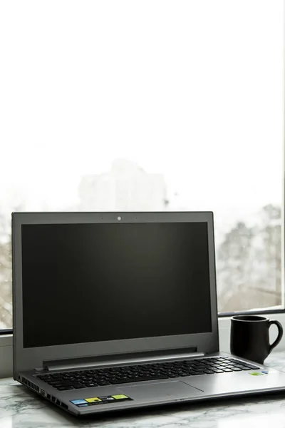 Laptop számítógép áll a márvány tábla az ablak, egy csésze kávé mellett — Stock Fotó