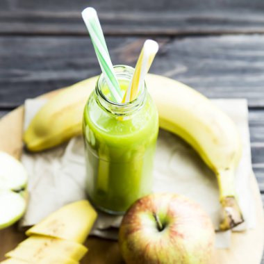 ham elma ve muz sarı ve yeşil bir tüp ile şeffaf şişede taze meyve suyu