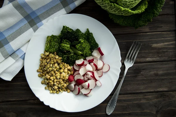 Rawfoodist vegan salade vrolijkheid van kool, radijs spruiten en linzen op een witte plaat — Stockfoto