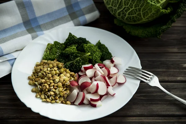 Rawfoodist vegan salade vrolijkheid van kool, radijs spruiten en linzen op een witte plaat — Stockfoto